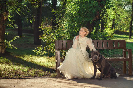 Girl in an old dress with ruffles and a big dark dogの写真素材
