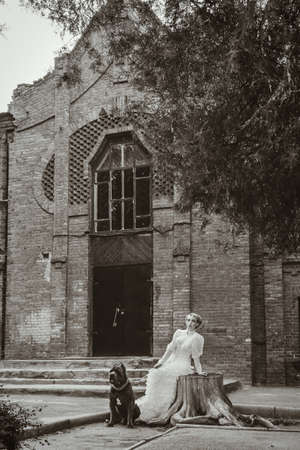 Girl in an old dress with ruffles and a big dark dogの写真素材