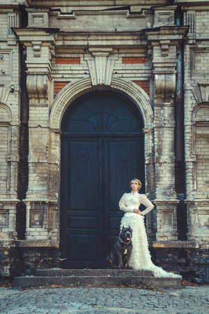 Girl in an old dress with ruffles and a big dark dogの写真素材
