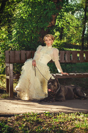Girl in an old dress with ruffles and a big dark dogの写真素材