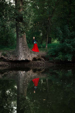 Girl model with white hair in a retro dress with ruffles in a green parkの写真素材