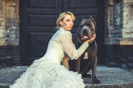 Girl in an old dress with ruffles and a big dark dogの写真素材