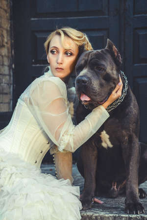 Girl in an old dress with ruffles and a big dark dogの写真素材