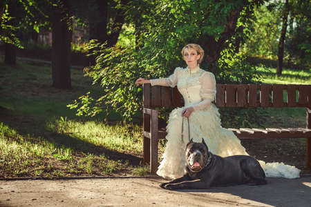 Girl in an old dress with ruffles and a big dark dogの写真素材