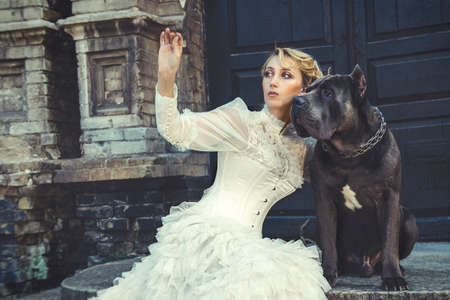 Girl in an old dress with ruffles and a big dark dogの写真素材