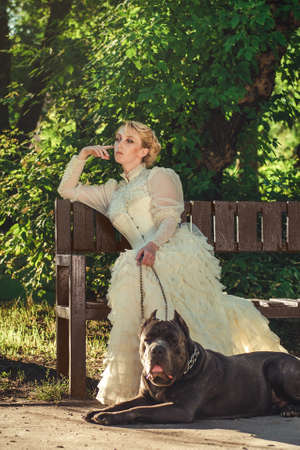 Girl in an old dress with ruffles and a big dark dogの写真素材