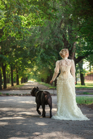 Girl in an old dress with ruffles and a big dark dogの写真素材