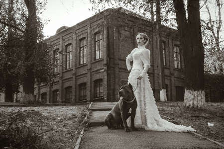 Girl in an old dress with ruffles and a big dark dogの写真素材