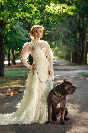 Girl in an old dress with ruffles and a big dark dogの写真素材