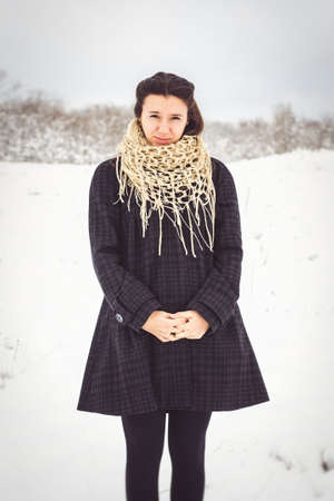girl in warm clothes and scarves on a walk in the snowy forest and in the fieldの写真素材