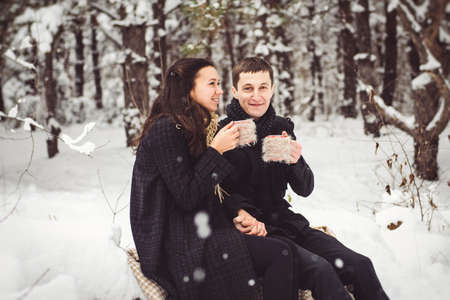A guy and a girl in warm clothes and scarves on a walk in the snowy forest and in the fieldの写真素材