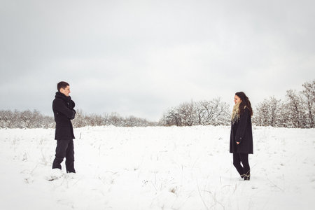 A guy and a girl in warm clothes and scarves on a walk in the snowy forest and in the fieldの写真素材
