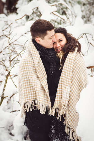 A guy and a girl in warm clothes and scarves on a walk in the snowy forest and in the fieldの写真素材