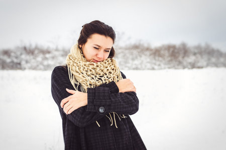 girl in warm clothes and scarves on a walk in the snowy forest and in the fieldの写真素材