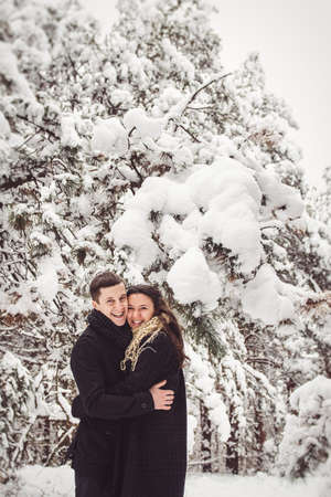 A guy and a girl in warm clothes and scarves on a walk in the snowy forest and in the fieldの写真素材