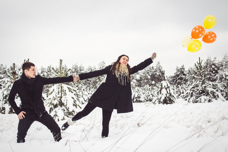 A guy and a girl in warm clothes and scarves on a walk in the snowy forest and in the fieldの写真素材