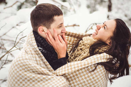 A guy and a girl in warm clothes and scarves on a walk in the snowy forest and in the fieldの写真素材