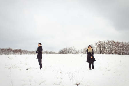 A guy and a girl in warm clothes and scarves on a walk in the snowy forest and in the fieldの写真素材