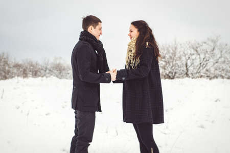A guy and a girl in warm clothes and scarves on a walk in the snowy forest and in the fieldの写真素材