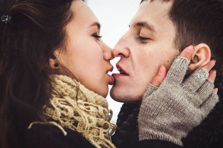 A guy and a girl in warm clothes and scarves on a walk in the snowy forest and in the fieldの写真素材