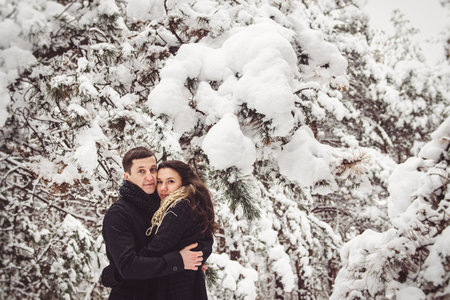 A guy and a girl in warm clothes and scarves on a walk in the snowy forest and in the fieldの写真素材