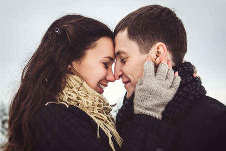 A guy and a girl in warm clothes and scarves on a walk in the snowy forest and in the fieldの写真素材
