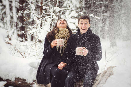 A guy and a girl in warm clothes and scarves on a walk in the snowy forest and in the fieldの写真素材