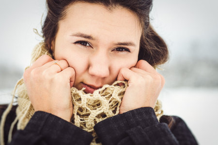 girl in warm clothes and scarves on a walk in the snowy forest and in the fieldの写真素材
