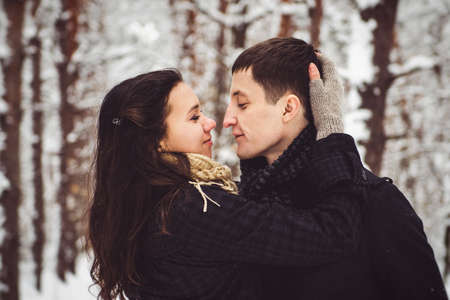 A guy and a girl in warm clothes and scarves on a walk in the snowy forest and in the fieldの写真素材
