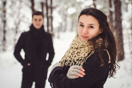 A guy and a girl in warm clothes and scarves on a walk in the snowy forest and in the fieldの写真素材