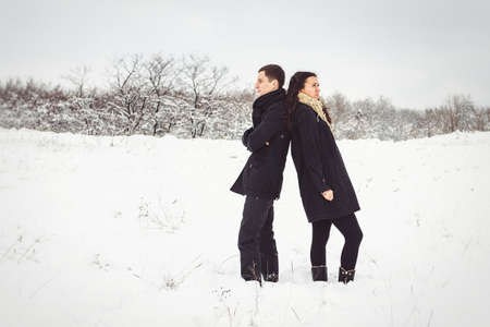 A guy and a girl in warm clothes and scarves on a walk in the snowy forest and in the fieldの写真素材