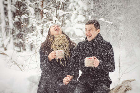 A guy and a girl in warm clothes and scarves on a walk in the snowy forest and in the fieldの写真素材
