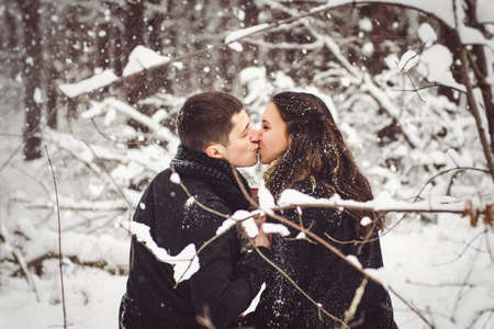 A guy and a girl in warm clothes and scarves on a walk in the snowy forest and in the fieldの写真素材