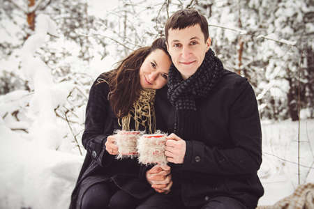 A guy and a girl in warm clothes and scarves on a walk in the snowy forest and in the fieldの写真素材