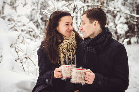 A guy and a girl in warm clothes and scarves on a walk in the snowy forest and in the fieldの写真素材