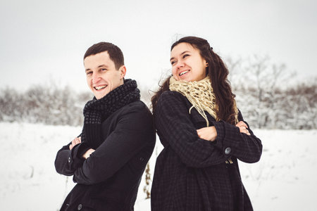 A guy and a girl in warm clothes and scarves on a walk in the snowy forest and in the fieldの写真素材