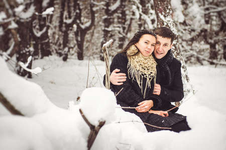 A guy and a girl in warm clothes and scarves on a walk in the snowy forest and in the fieldの写真素材