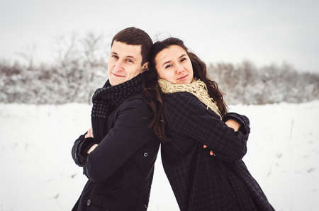 A guy and a girl in warm clothes and scarves on a walk in the snowy forest and in the fieldの写真素材