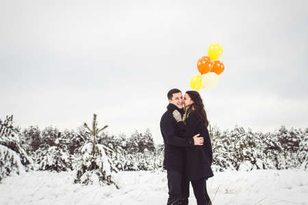 A guy and a girl in warm clothes and scarves on a walk in the snowy forest and in the fieldの写真素材