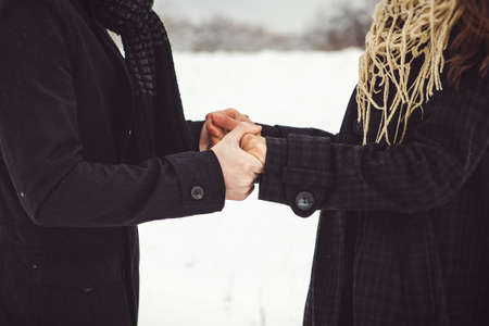 A guy and a girl in warm clothes and scarves on a walk in the snowy forest and in the fieldの写真素材