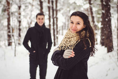 A guy and a girl in warm clothes and scarves on a walk in the snowy forest and in the fieldの写真素材