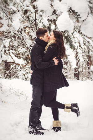 A guy and a girl in warm clothes and scarves on a walk in the snowy forest and in the fieldの写真素材