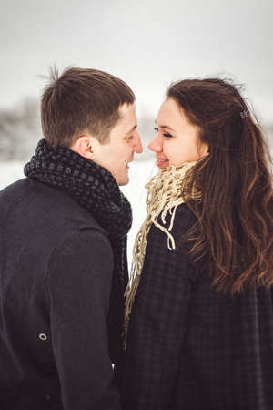 A guy and a girl in warm clothes and scarves on a walk in the snowy forest and in the fieldの写真素材