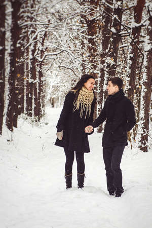 A guy and a girl in warm clothes and scarves on a walk in the snowy forest and in the fieldの写真素材