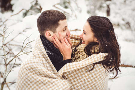 A guy and a girl in warm clothes and scarves on a walk in the snowy forest and in the fieldの写真素材