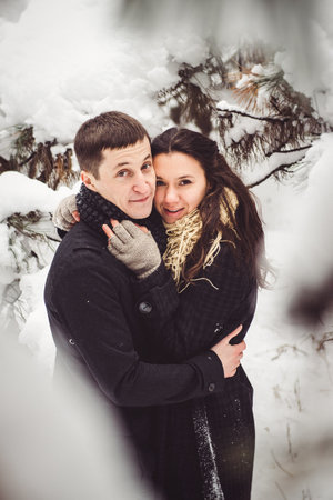 A guy and a girl in warm clothes and scarves on a walk in the snowy forest and in the fieldの写真素材