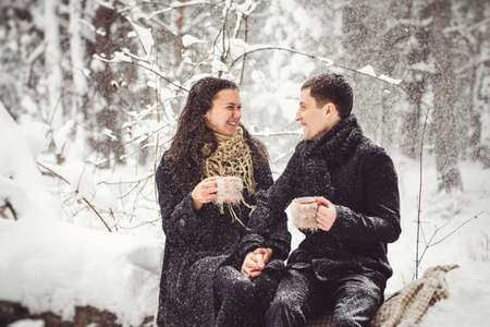 A guy and a girl in warm clothes and scarves on a walk in the snowy forest and in the fieldの写真素材