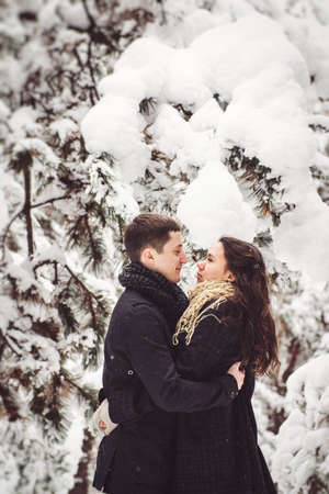 A guy and a girl in warm clothes and scarves on a walk in the snowy forest and in the fieldの写真素材