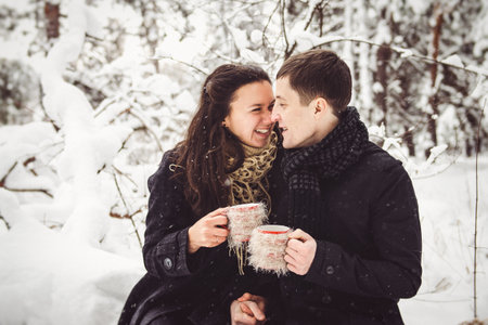 A guy and a girl in warm clothes and scarves on a walk in the snowy forest and in the fieldの写真素材