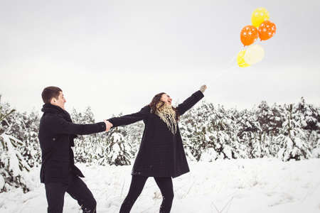 A guy and a girl in warm clothes and scarves on a walk in the snowy forest and in the fieldの写真素材